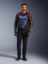 Blouson en cuir Alpinestars GP Force V2, noir, bleu et rouge fluo, porté par un mannequin homme avec un pantalon noir et des gants de moto, blouson de moto sport en cuir de vachette au design inspiré de la course, vue de face