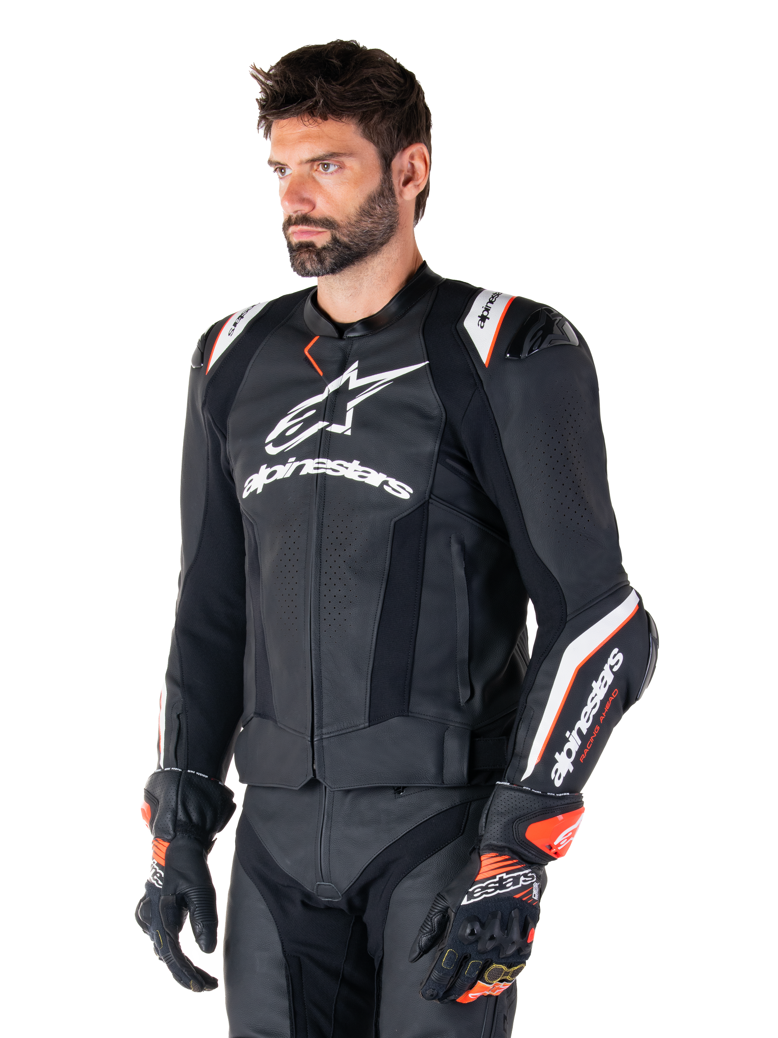 Modèle masculin portant la veste en cuir Alpinestars Missile V3 Ignition, noir avec des accents blancs et orange, dotée de logos blancs distinctifs, de sections en cuir perforé et de protections d'épaules, avec des gants de course pour un look sport-racing.