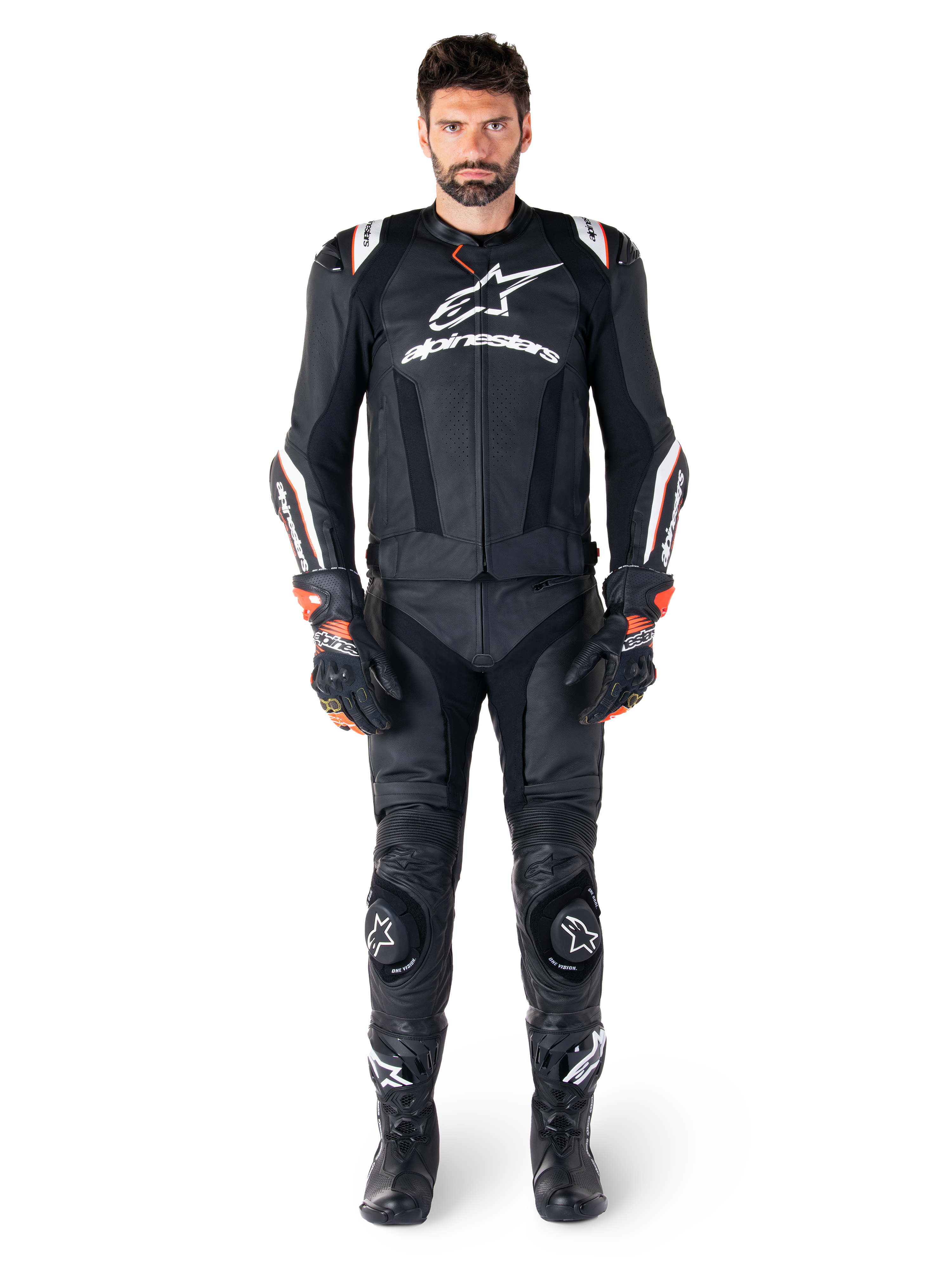 Pilote portant la veste en cuir Alpinestars Missile V3 Ignition en noir, associée à un pantalon en cuir, des gants et des bottes assortis, avec logos Alpinestars blancs et accents rouges, conçue pour la performance de course professionnelle.