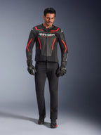 Pilote portant le blouson en cuir Alpinestars GP Force V2 Air, noir et rouge fluo, associé à un jean de moto noir, des gants et des chaussures, avec une construction en cuir perforé, des logos blancs et des accents rouges élégants pour un look sportif