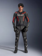 Mannequin homme portant la veste en cuir Alpinestars GP Force V2 Air en noir et rouge fluo, avec panneaux de poitrine perforés et logos blancs, associée à un pantalon de moto en cuir noir, des gants noirs et des bottes noires pour une tenue de course complète.