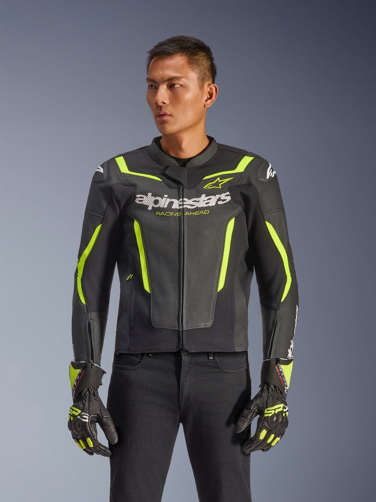 Blouson en cuir Alpinestars GP Force V2 Air, noir et jaune fluo, blouson de moto en cuir perforé avec protections et accents néon, porté avec des gants de course assortis et un pantalon noir, coupe sport athlétique avec marquage distinctif