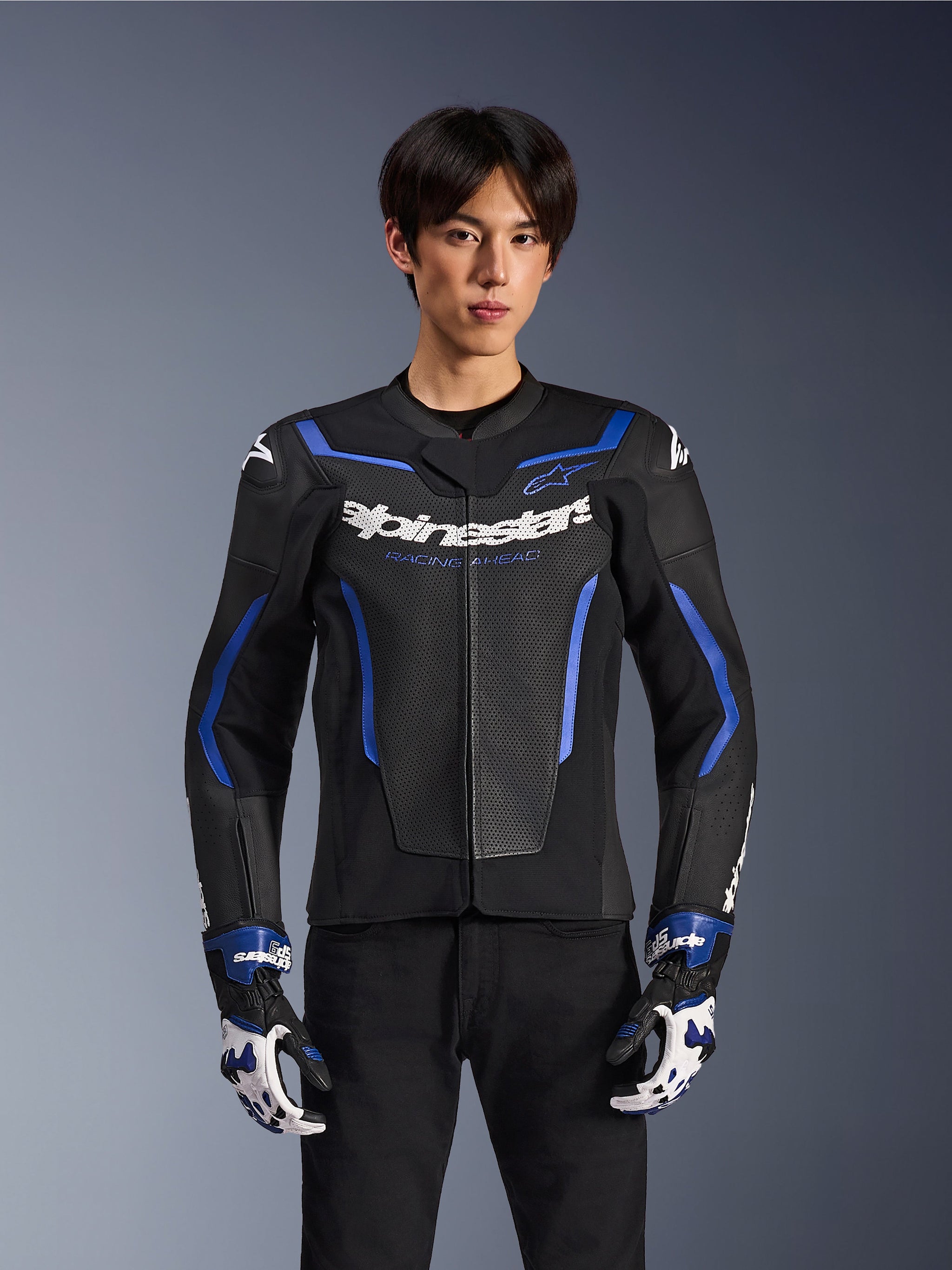 Blouson en cuir Alpinestars GP Force V2 Airflow, Noir Bleu Métallique, blouson de moto avec cuir perforé et accents bleus, porté par un mannequin avec des gants de course assortis et un pantalon noir, équipement de conduite sportive professionnel