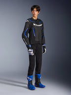 Pilote masculin portant le blouson en cuir GP Force V2 Airflow en Noir Bleu Métallisé, associé à des gants de course assortis et des bottes bleues, avec du cuir perforé et un marquage Alpinestars affirmé, équipement de route professionnel pour moto.