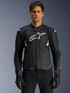 Veste en cuir Alpinestars Dusk Airflow, noir et blanc, veste de moto en cuir portée par un mannequin, avec panneaux en cuir perforé pour la ventilation, un grand logo blanc sur la poitrine et des sliders d'épaule externes.