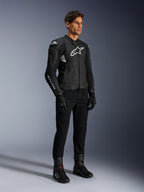Veste en cuir Alpinestars Dusk Airflow, noir et blanc, portée avec un pantalon de moto, des gants et des bottes noirs, avec panneaux en cuir perforé et logos blancs, style sport road racing