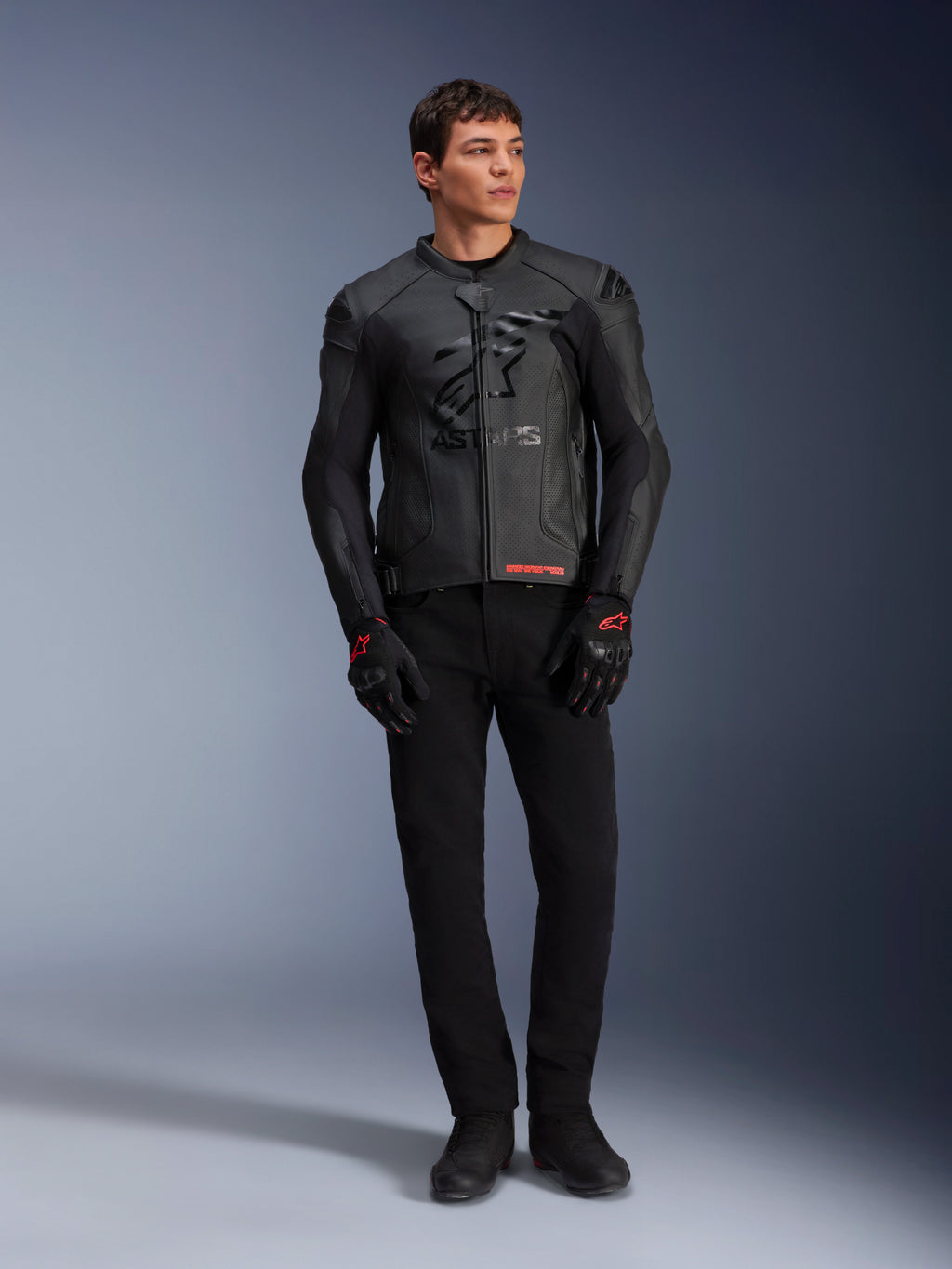 Veste en cuir Alpinestars GP Plus R V4 Airflow, noire, portée par un mannequin homme avec gants et pantalon noirs assortis, avec panneaux en cuir perforé, grand logo étoile ton sur ton sur la poitrine et coupe sport ajustée