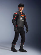 Pilote portant une veste en cuir Alpinestars GP Plus R V4 Airflow, noir avec des accents rouge fluo et blanc, dotée de cuir perforé et du logo ASTARS sur la poitrine, avec pantalon de moto noir et bottes de moto noires, équipement de performance sportive