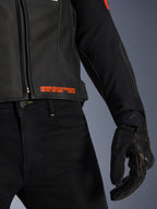 Veste en cuir Alpinestars GP Plus R V4 Airflow, gros plan sur la taille et la manche, cuir noir perforé avec marquage rouge fluo « Advanced Racewear Engineering », associée à un pantalon de moto noir et un gant de moto SPX 7