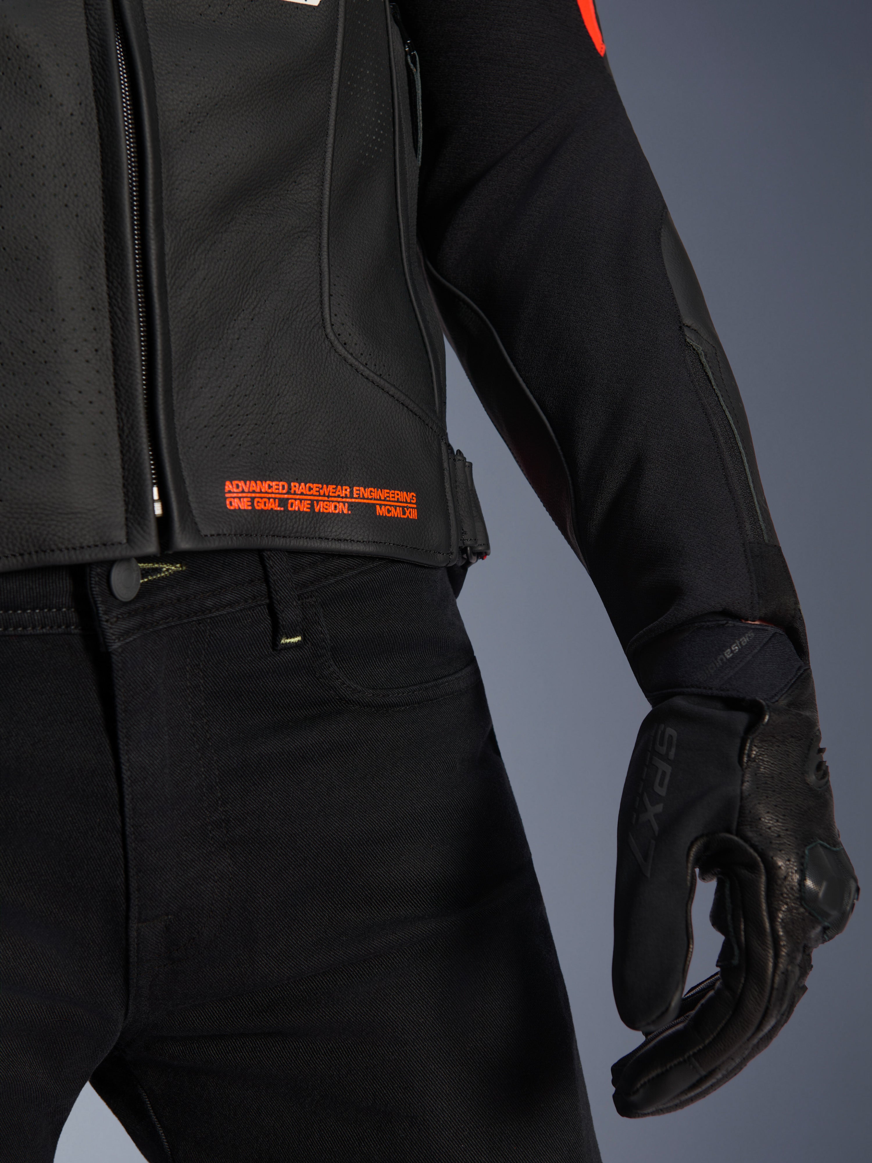 Veste en cuir Alpinestars GP Plus R V4 Airflow, gros plan sur la taille et la manche, cuir noir perforé avec marquage rouge fluo « Advanced Racewear Engineering », associée à un pantalon de moto noir et un gant de moto SPX 7