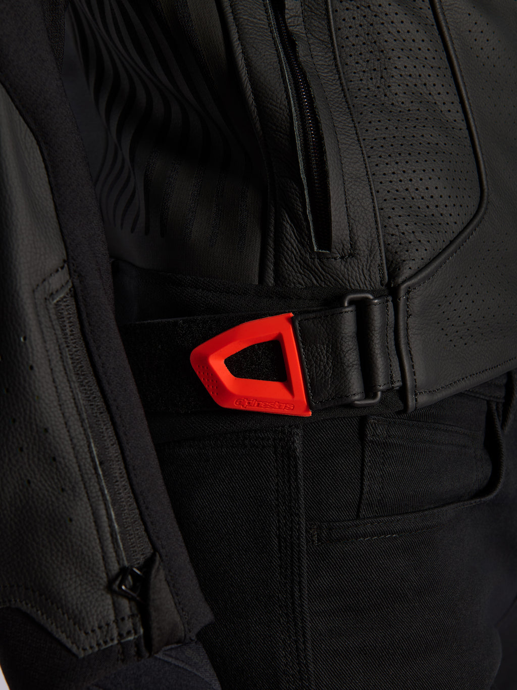 Veste en cuir Alpinestars GP Plus R V4 Airflow, gros plan, cuir perforé noir avec une sangle de réglage de la taille à crochet et boucle rouge fluo éclatant, dotée d'une poche latérale zippée et de panneaux texturés ergonomiques.
