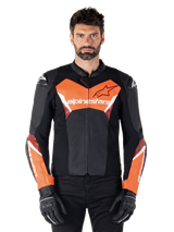 Veste en cuir Alpinestars Faster V3, veste de moto sportive, noir et rouge fluo, portée par un mannequin homme avec gants et pantalon de moto noirs, logo Alpinestars imposant sur la poitrine et les avant-bras, construction en cuir haut de gamme pour la route.