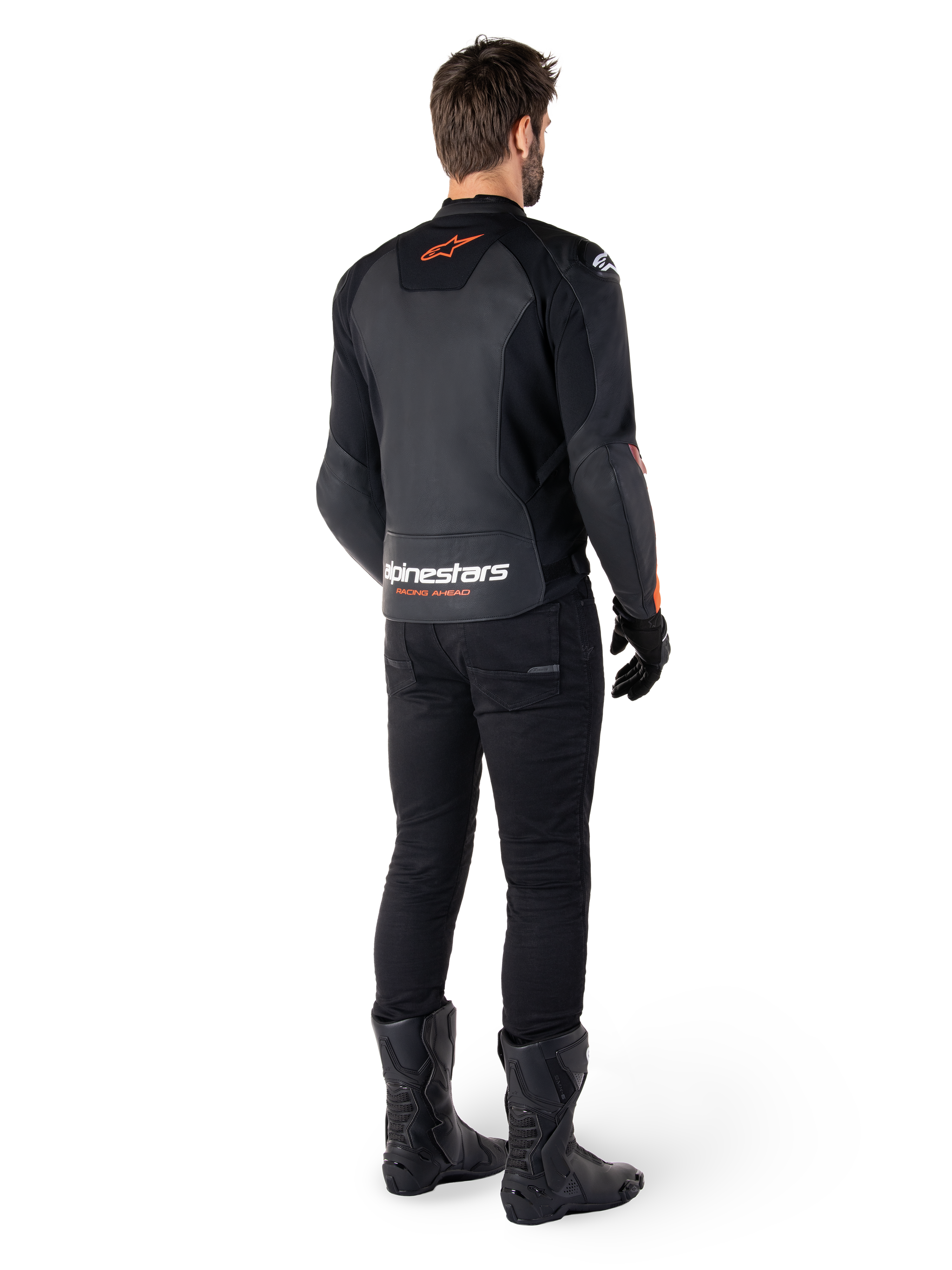 Veste en cuir Alpinestars Faster V3, veste de moto sportive, noir et rouge fluo, vue de dos portée avec un pantalon noir et des bottes noires, arborant l'inscription « alpinestars RACING AHEAD » sur le bas du dos et un petit logo d'étoile rouge, construction en cuir à coupe sportive épurée