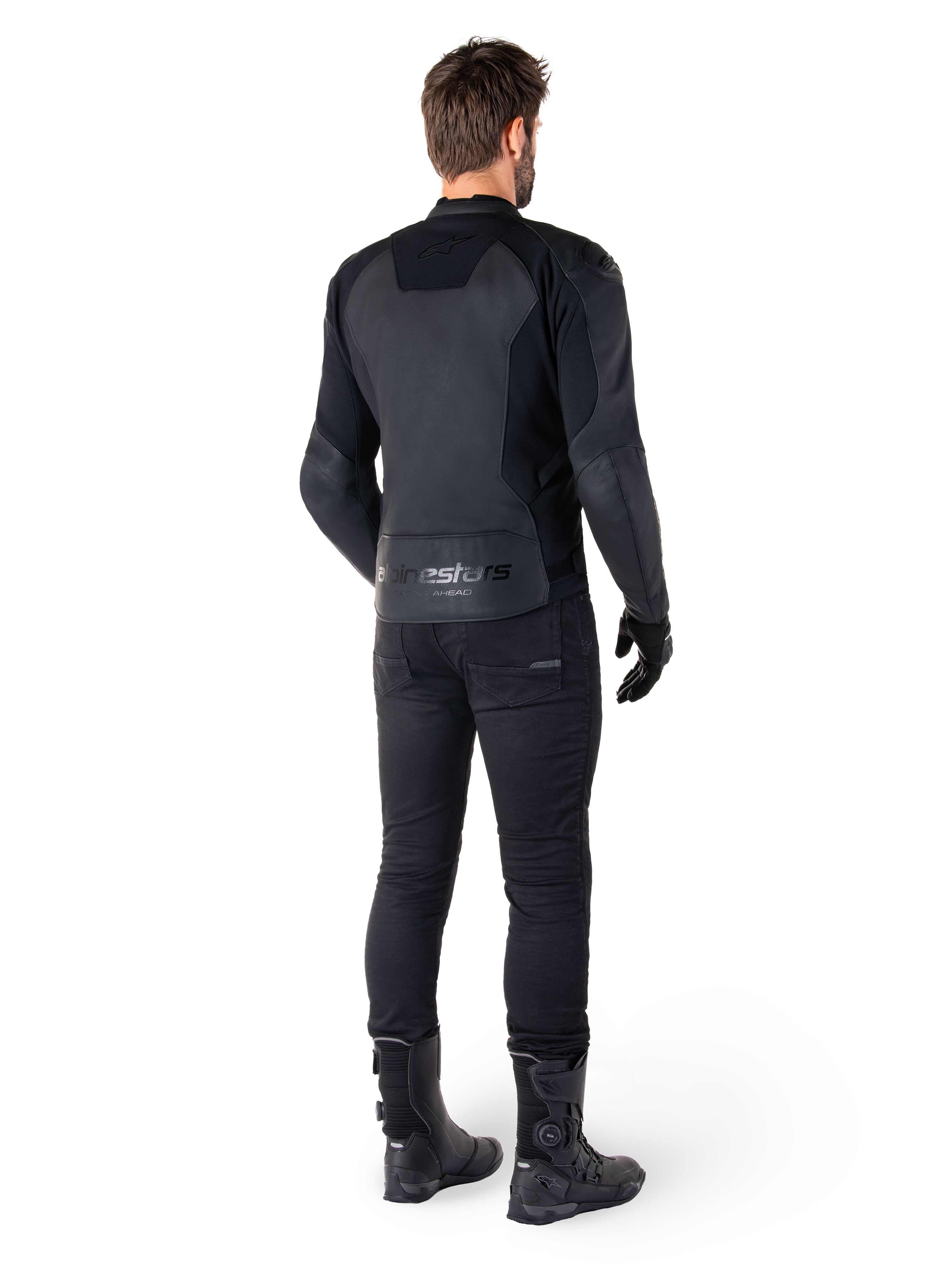 Veste en cuir Alpinestars Faster V3, Noir Noir, vue arrière sur un pilote, avec des panneaux en cuir haut de gamme et un marquage Alpinestars embossé, associée à un pantalon et des bottes de moto noirs pour un look de moto sportive complet.