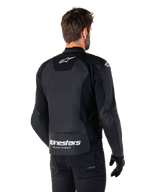 Veste en cuir Alpinestars Faster V3, noir et blanc, vue arrière sur un pilote, avec logo étoile blanc sur le haut du dos et grand marquage Alpinestars avec « Racing Ahead » sur le bas du dos, dos allongé pour une meilleure couverture, construction en cuir sport haut de gamme