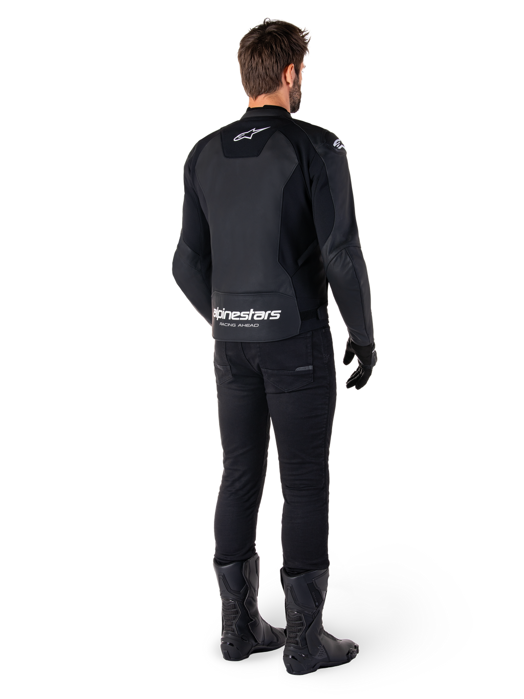 Veste en cuir Alpinestars Faster V3, vue de dos, noir et blanc, avec marquage 'alpinestars RACING AHEAD' sur le bas du dos, portée avec un pantalon et des bottes de moto noirs, veste de moto en cuir d'inspiration sportive avec panneaux extensibles