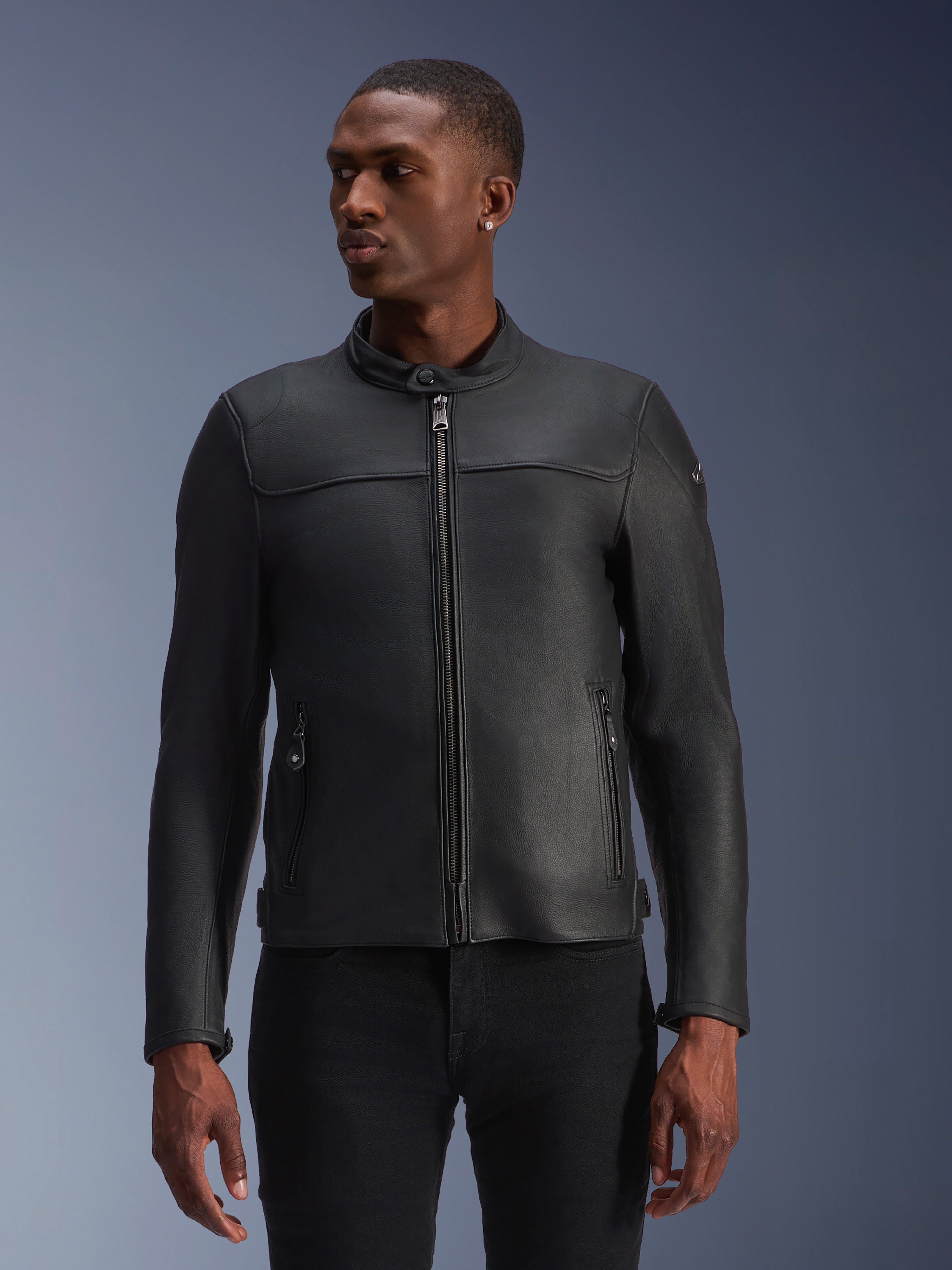 Veste en cuir Alpinestars Blacktrack, noire, veste de moto, portée par un mannequin, dotée d'une fermeture éclair frontale métallique, d'un col haut et de poches zippées, construction en cuir premium pour un look moderne et minimaliste