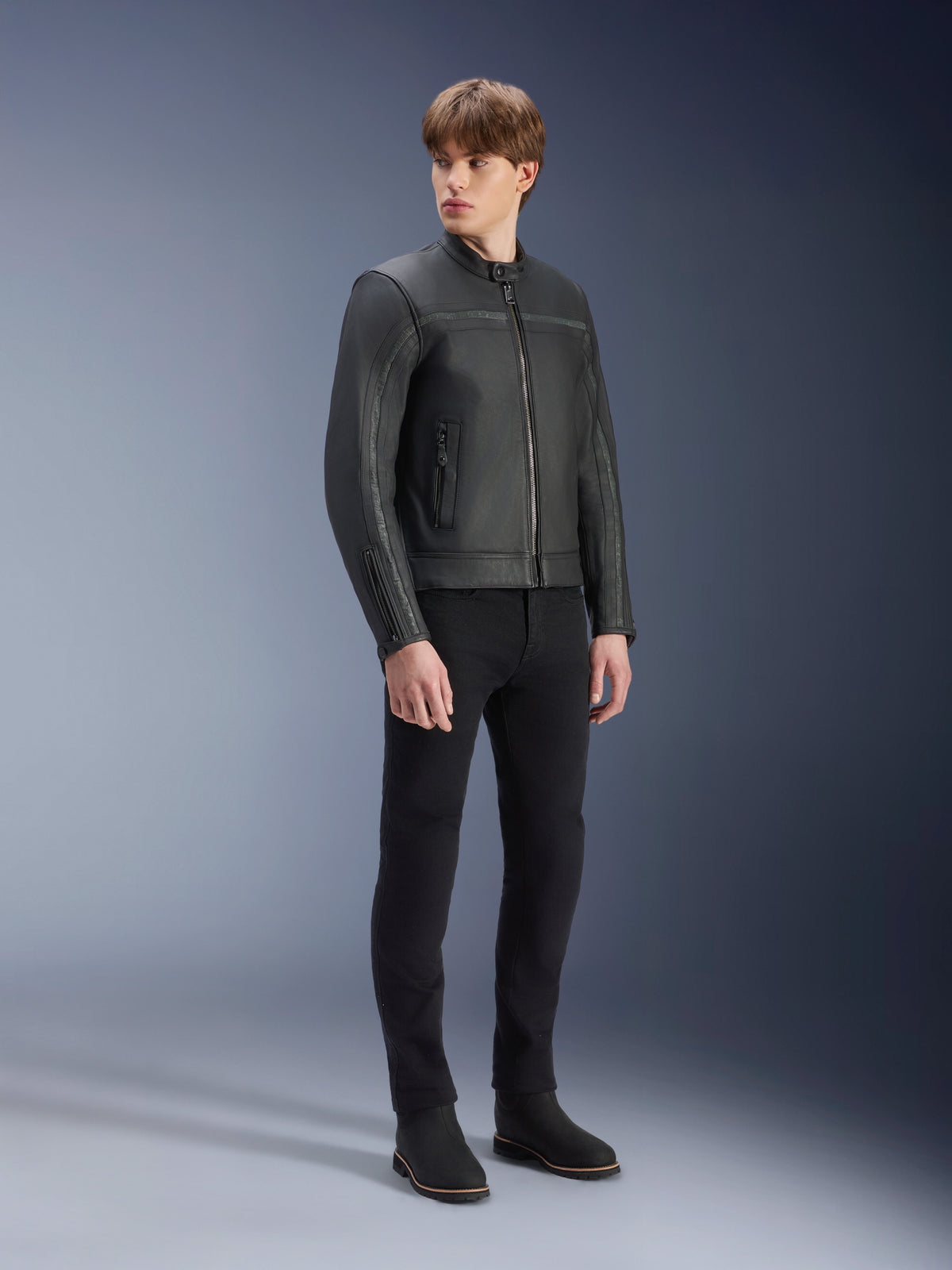 Blouson en cuir Alpinestars Dyno en Noir, veste de moto en cuir de bovin de première qualité, portée par un mannequin homme avec un pantalon slim noir et des bottes noires, design minimaliste d'inspiration héritage pour la conduite urbaine contemporaine, décor de studio.