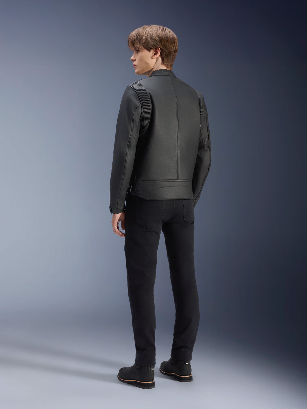 Alpinestars Dyno Leather Jacket, Black, worn by a male model from the rear view, featuring ribbed shoulder panels, paired with black pants and boots, heritage-inspired urban motorcycle style.