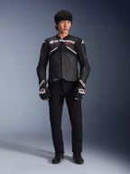 Mannequin portant la veste en cuir Alpinestars Atem V5 en noir et blanc, avec le logo Alpinestars blanc et un logo d'étoile rouge sur la poitrine, associée à un pantalon noir et des gants de course noir et blanc, équipement de moto performant et élégant