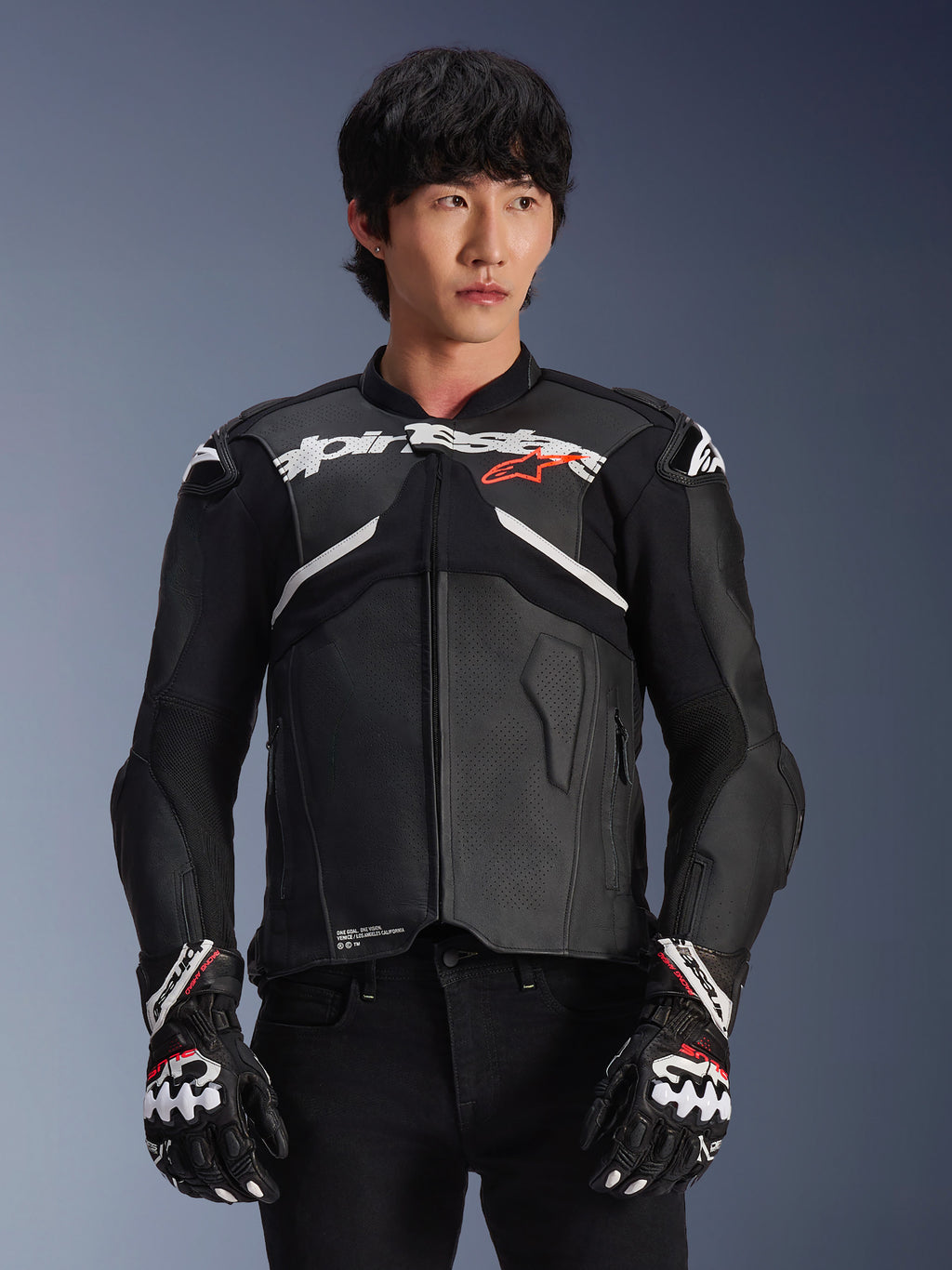 Veste en cuir Alpinestars Atem V5, veste de course de moto, noire avec des accents blancs et rouges, construction en cuir premium avec protections renforcées, portée avec des gants de course assortis