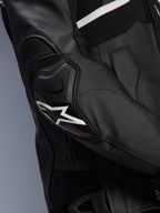Veste en cuir Alpinestars Atem V5, noir et blanc, gros plan sur la protection de coude DFS RR avec logo étoile blanc, dotée de cuir en accordéon et de textures perforées pour une conduite sportive