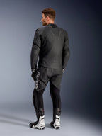 Veste en cuir Alpinestars Caliber, blouson de moto de route noir, vue de dos, avec cuir perforé et inserts stretch accordéon à la taille et aux épaules, logo en relief, porté avec un pantalon en cuir noir et des bottes de course blanches