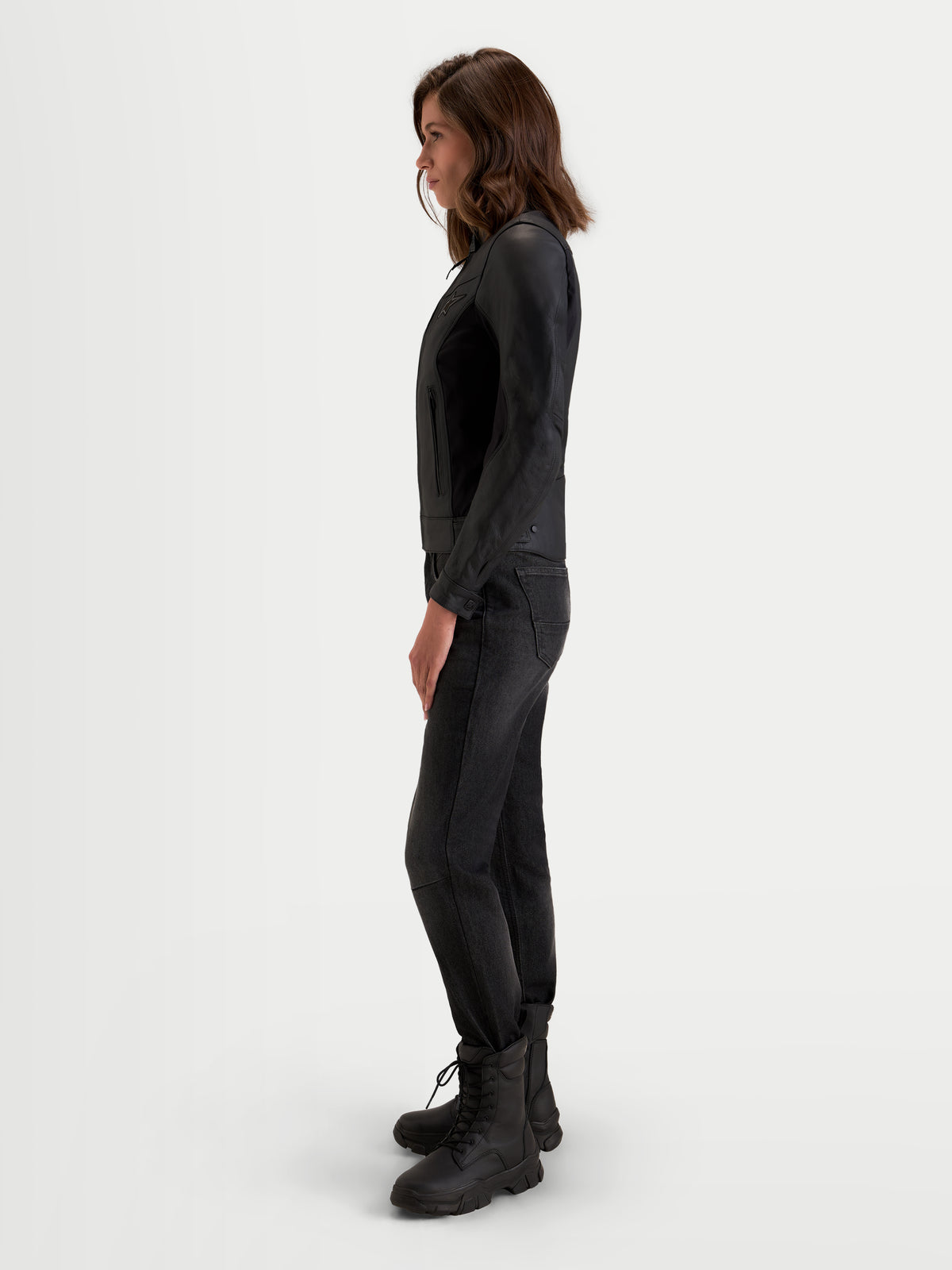 Alpinestars Stella Maver X Veste en cuir, veste de moto urbaine contemporaine pour femme noire, vue de profil portée par un modèle mettant en valeur la coupe ajustée et la construction en cuir