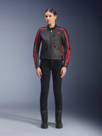 Veste en cuir Alpinestars Stella Dyno, veste de moto pour femme, noir et rouge, avec des bandes de course rouges sur les épaules et les manches, logo étoile rouge sur la poitrine, portée avec un pantalon slim noir et des bottes, cuir de bovin de première qualité au design moderne et classique