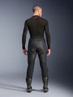 Alpinestars Missile V3 Leather Pants, Black, rear view on model wearing a black long-sleeve compression shirt and racing boots, premium leather construction with high-waist overlap and stretch zones, professional motorcycle racing gear