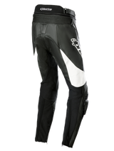 Alpinestars Stella Missile V3 Leather Pants, pantalon de moto de course pour femme, noir avec accents blancs, vue de trois-quarts arrière montrant des panneaux extensibles en accordéon au bas du dos, logo Alpinestars sur la cuisse et sliders de genou intégrés pour le pilotage sportif.