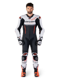 Alpinestars GP-R7 1 pièce, combinaison en cuir pour homme, blanche, noire et rouge fluo, portée avec gants et bottes.