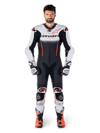 Alpinestars GP-R7 1 pièce, combinaison en cuir pour homme, blanche, noire et rouge fluo, portée avec gants et bottes.