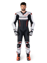 Male rider wearing the Alpinestars GP-R7 One Piece Leather Suit in White Black and Red Fluo, coordinated with matching racing gloves and boots, professional motorcycle track gear featuring a streamlined race fit and bold branding