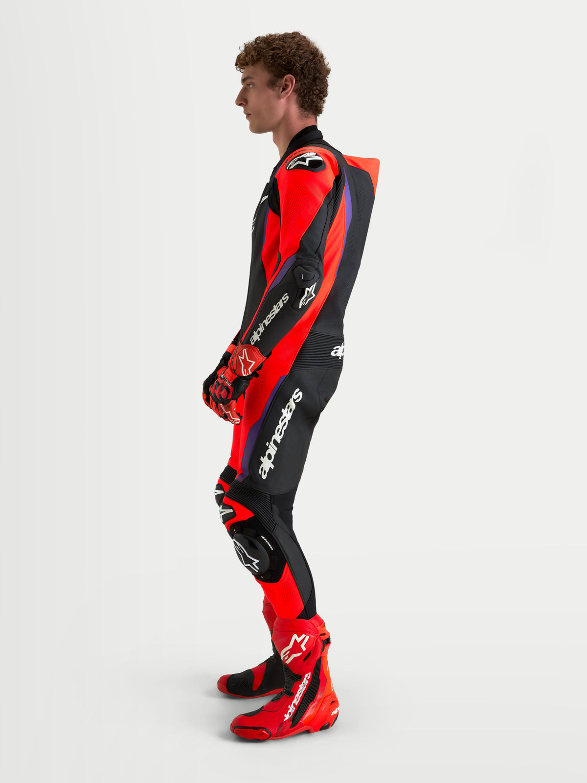 Combinaison en cuir Missile V 3 Leather 1 Pc d'Alpinestars, combinaison moto racing pour homme, noire, rouge et violette, avec bosse aérodynamique, vue de profil