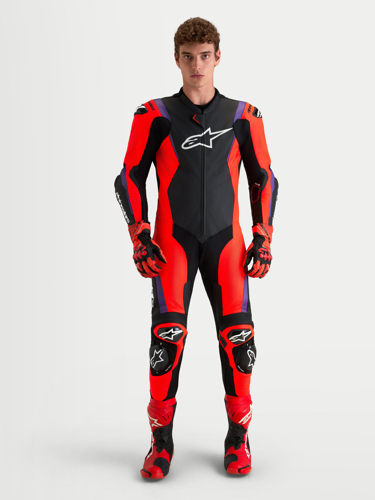 Combinaison en cuir Missile V3 1 pièce d'Alpinestars, combinaison moto racing pour homme noire, rouge et violette, portée par un modèle