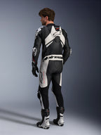 Alpinestars combinaison en cuir GP Plus V4 Sprint 1 pièce pour homme, noire et blanche, technologie A-CS®, certifiée CE AAA, vue arrière d'un pilote avec bosse aérodynamique.