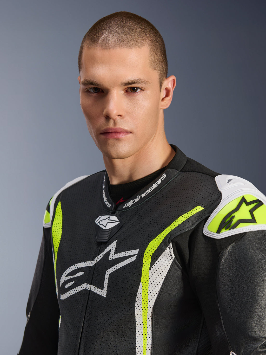Gros plan d'un mannequin homme portant la combinaison en cuir une pièce Alpinestars GP Tech V5, Noir Blanc Jaune Fluo, avec cuir perforé, logos Alpinestars blancs sur la poitrine et les épaules, et accents jaune vif, équipement de course professionnel.
