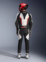 Combinaison en cuir Alpinestars GP Force V2 - 1 pièce, blanc, noir et rouge fluo, vue arrière mettant en évidence la bosse aérodynamique et le logo Tech-Air Ready, portée avec un casque de course rouge et des bottes blanches et noires, conçue pour la performance sur piste