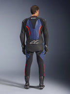 Combinaison en cuir Alpinestars GP Force V2 2 pièces, vue arrière, noir, bleu et rouge fluo, avec des panneaux en cuir bleu sur le dos et les jambes et des accents rouge fluo, marquage Tech-Air Ready en bas du dos, portée avec des gants et bottes de course noirs.