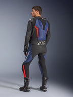 Combinaison en cuir 2 pièces GP Force V2, noir, bleu et rouge fluo, vue de profil arrière sur un mannequin, avec bosse aérodynamique, cuir perforé et logo Tech-Air Ready, portée avec des bottes et gants de course Alpinestars noirs