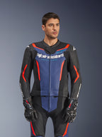 Modèle masculin portant la combinaison en cuir Alpinestars GP Force V2 2 pièces, noir bleu rouge fluo, avec un empiècement bleu sur la poitrine et des accents rouges, portée avec des gants GP Pro, équipement professionnel de course moto en cuir avec texture perforée.