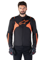 Alpinestars T-Jaws V4 Waterproof Jacket, veste de moto sport, noir et rouge fluo, avec des accents néon et un logo étoile proéminent sur la poitrine, portée par un modèle masculin avec des gants de moto noirs, design textile épuré inspiré de la course