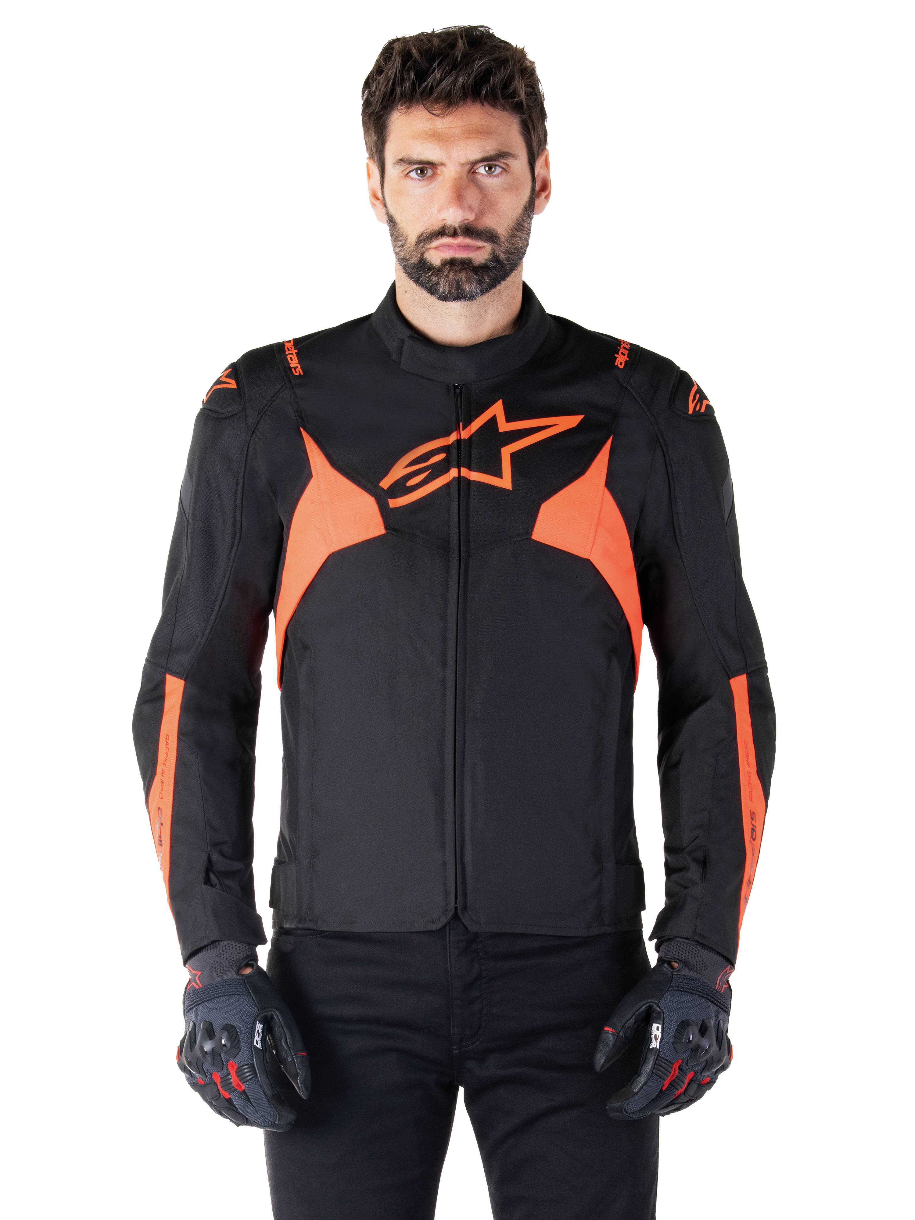 Alpinestars T-Jaws V4 Waterproof Jacket, veste de moto sport, noir et rouge fluo, avec des accents néon et un logo étoile proéminent sur la poitrine, portée par un modèle masculin avec des gants de moto noirs, design textile épuré inspiré de la course