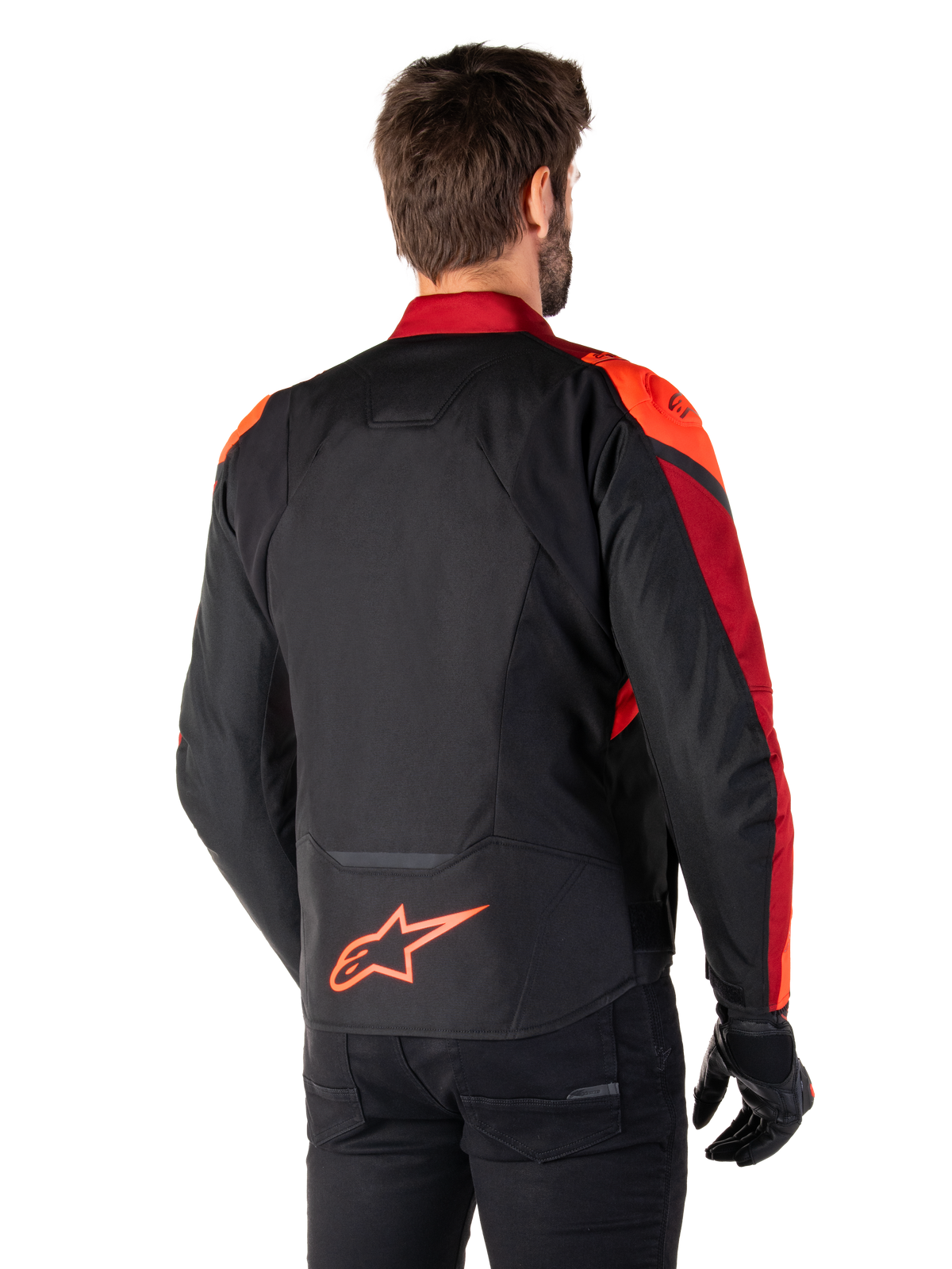 Vue de dos d'un homme portant la veste Alpinestars T-Jaws V4 Waterproof en Noir Rouge Fluo Rouge Foncé, avec des accents rouges vifs sur les épaules et les manches, un logo Alpinestars rouge fluo sur le bas du dos, accompagnée d'un pantalon et de gants noirs.