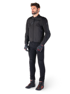 Male model wearing the Alpinestars T-Jaws V4 Waterproof Jacket in Black, paired with black riding pants, black gloves with red accents, and black motorcycle shoes, featuring a sleek sport fit and subtle branding, isolated on a white background.