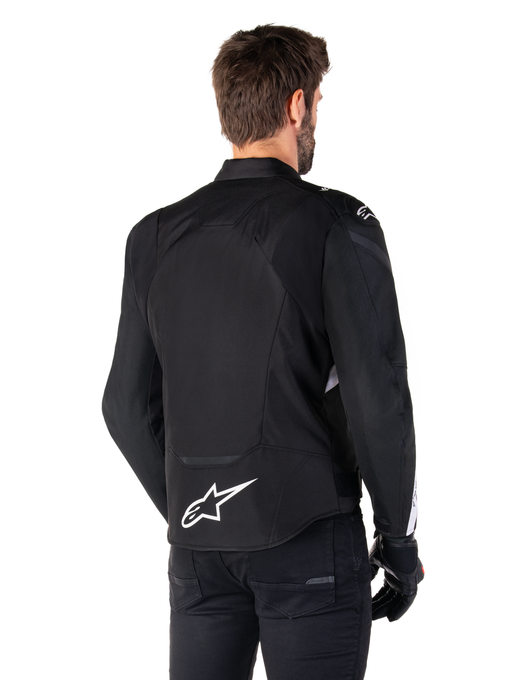 Veste étanche Alpinestars T-Jaws V4, noir et blanc, vue arrière, veste de moto sport en textile avec logo blanc sur le bas du dos, portée avec des gants et un pantalon noirs, présentant une silhouette à coupe sport révisée