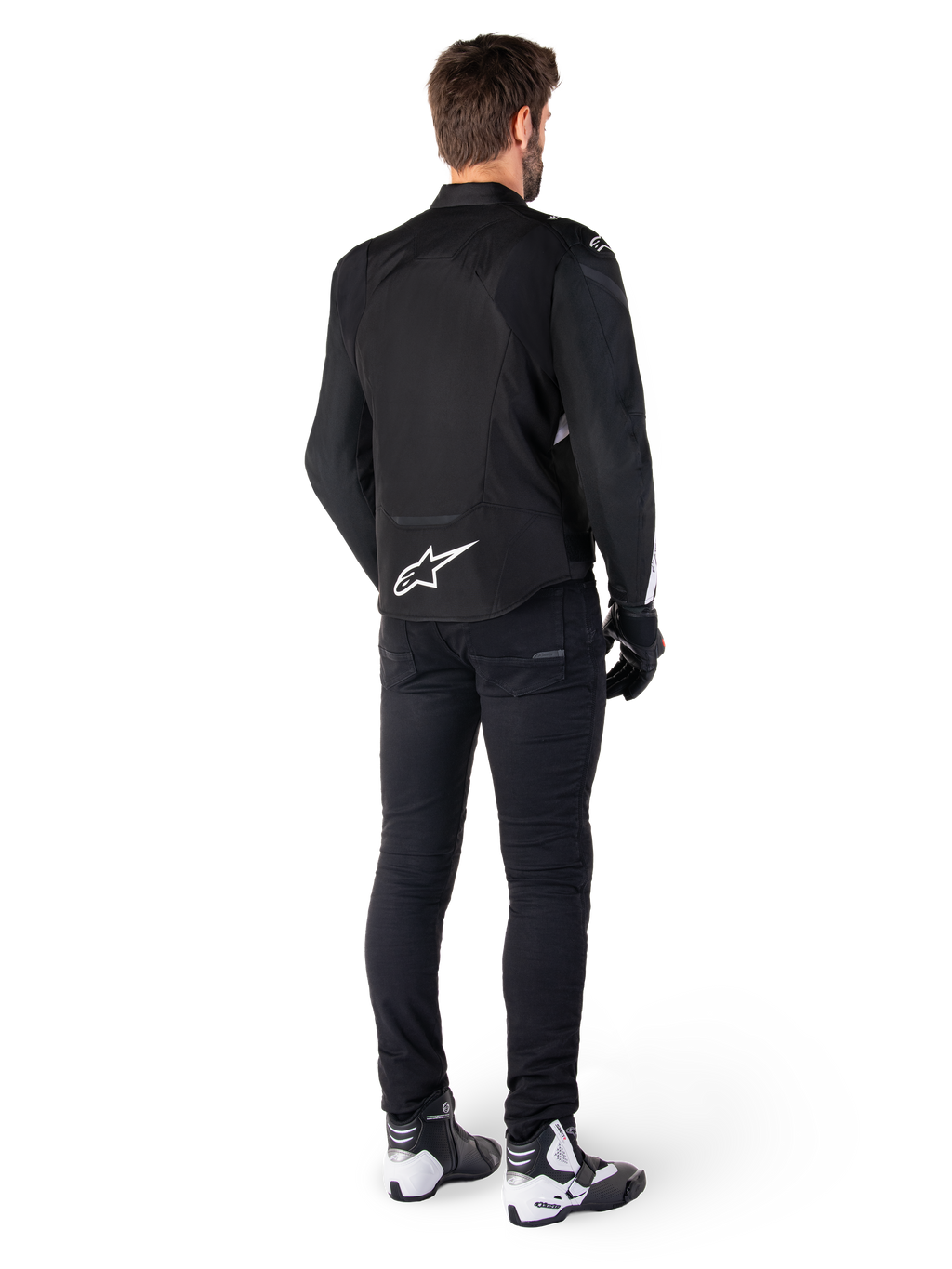 Veste imperméable Alpinestars T-Jaws V4, noir et blanc, vue arrière montrant le logo étoile blanc sur le bas du dos, portée par un mannequin avec un pantalon de moto noir, des gants noirs et des bottes de moto blanches et noires