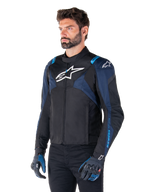 Alpinestars T-Jaws V4 Waterproof Jacket, Motorcycle Jacket, Black Dark Blue and Blithe Blue, worn by a model with matching gloves and black pants, featuring white Alpinestars logos on the chest and shoulders with blue accents on the sleeves, sporty textile riding gear