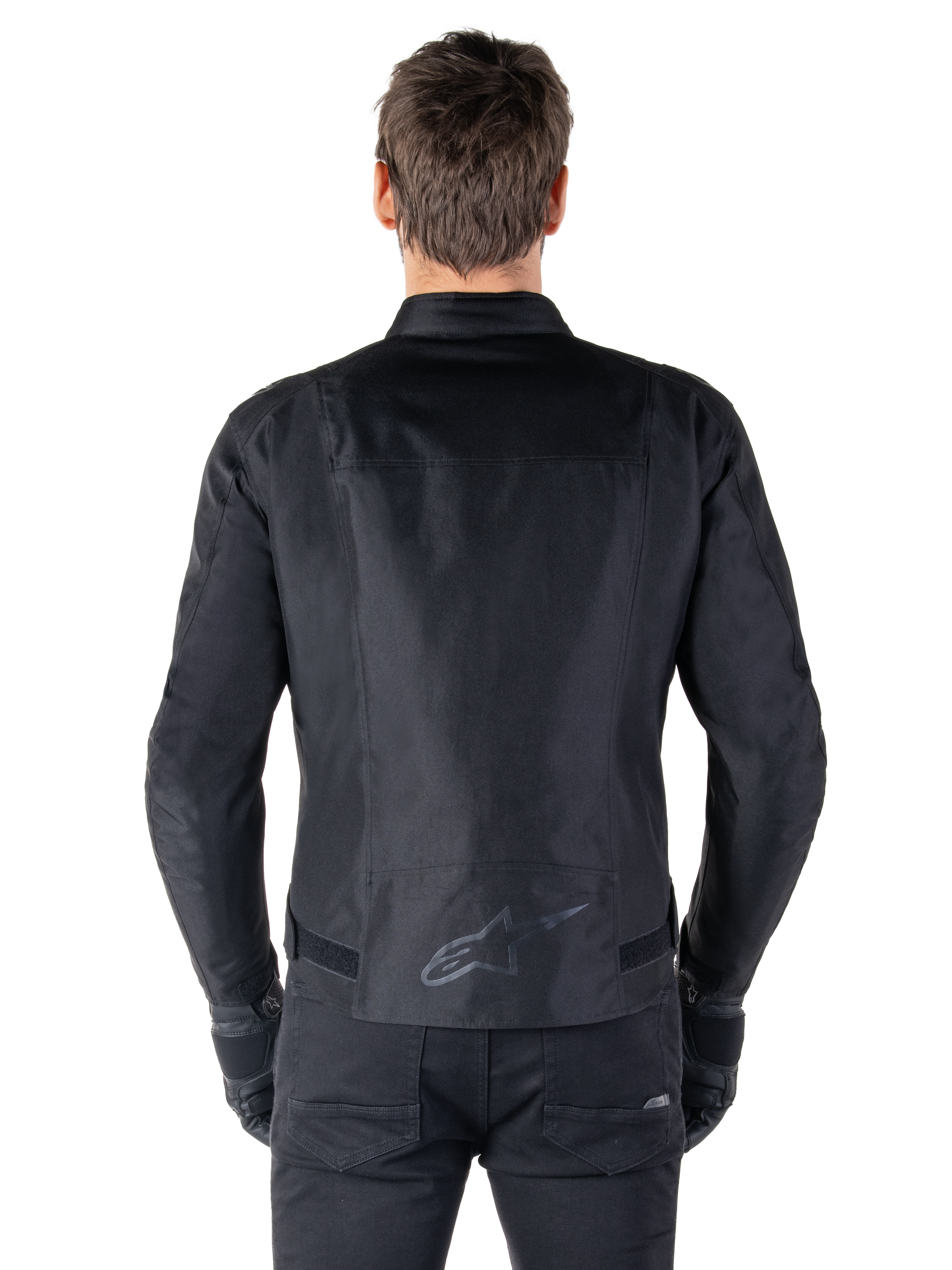 Veste Alpinestars T-SPS V2 Waterproof, noir, vue de dos montrant la silhouette à coupe sport, logo Alpinestars réfléchissant sur le bas du dos, et dos allongé pour une couverture supplémentaire en position de conduite.